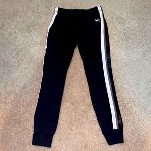 black sweatpants/joggers from pink. white, grey, and black stripes on the sides.